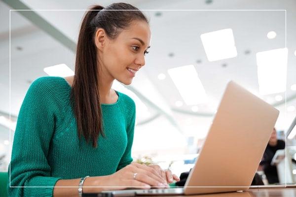 A woman smiling and looking at her laptop